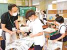 和田倫寛教諭（左）の助言を受けながら、水害に関する記事を探す児童＝松江市八幡町、竹矢小学校