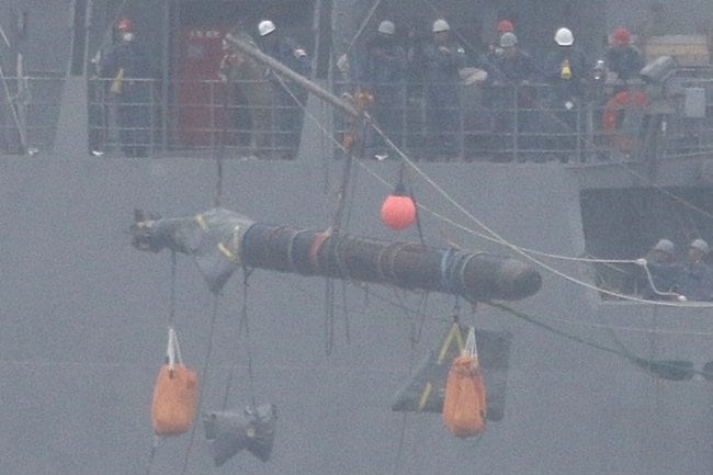 甲板に回収される、魚雷のような物体＝島根県隠岐の島町大久、大久漁港沖