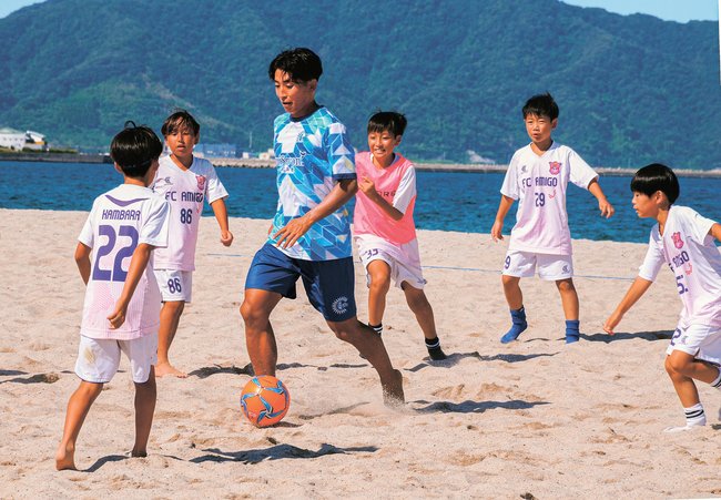 子どもたちとミニゲームを楽しむ坪谷亮太選手（中央）＝境港市佐斐神町の弓ケ浜