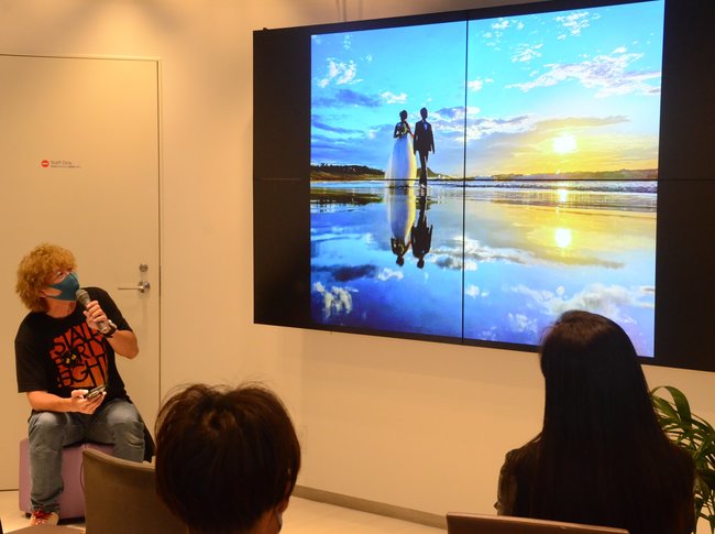 スマートフォンで撮影した鳥取砂丘の絶景を紹介する小椋宣洋さん(左)=東京都千代田区丸の内、東京シティアイ
