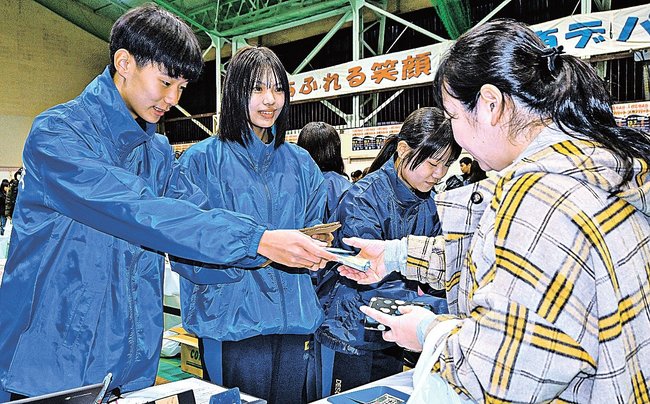 来場者に商品を渡す生徒＝浜田市熱田町、浜田商業高校
