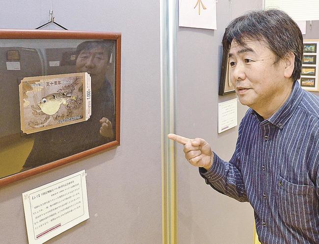 フグの干物が貼り付けられた記念切符を紹介する山道俊哉さん＝米子市中町、市立図書館