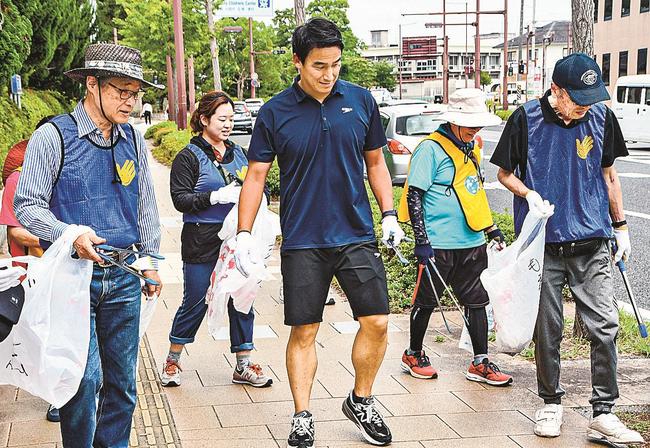 松田丈志さん（中央）とともにごみ拾いに汗を流す参加者＝米子市西町