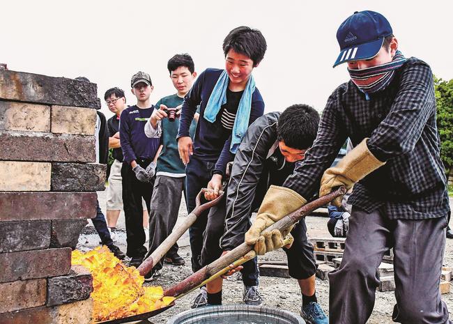 溶けた鉄の塊の「鉧出し」をする参加者＝出雲市斐川町直江、斐川西中学校
