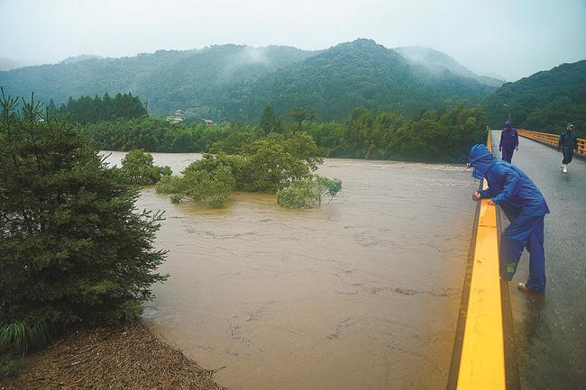 増水した高津川に流された男性を三星橋の上から捜す地元住民=9日午前8時20分、益田市神田町