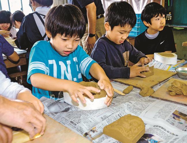 鬼瓦の型に粘土を押し込む児童＝浜田市黒川町、石見小学校