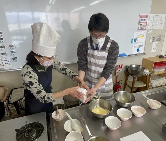 西尾尚美先生（左）からホワイトチョコチーズテリーヌの作り方を教わる記者