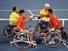 男子ダブルス１回戦に勝利し、拳を合わせる荒井（手前右）、三木組＝有明テニスの森公園