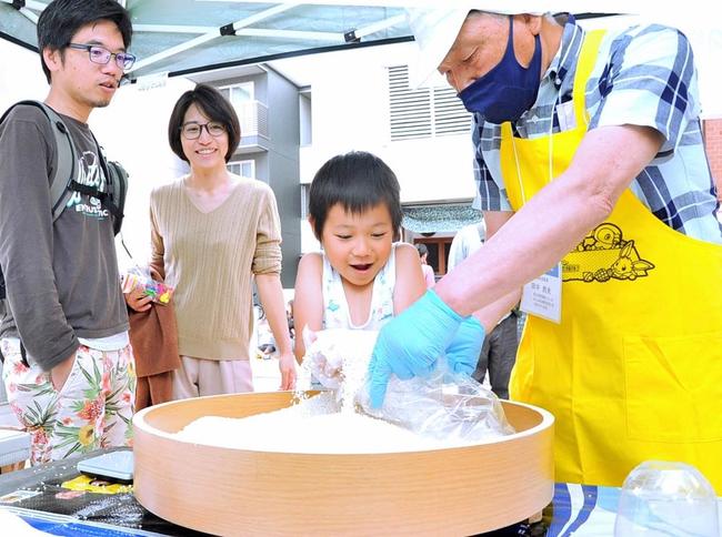 「こども食堂マルシェ」で、もち米のすくい取りに挑戦する来場者＝19日、松江市殿町の南殿町商店街