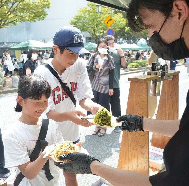 鳥取県産サツマイモ「紅はるか」などを使ったモンブランを受け取る来場者＝米子市末広町、米子コンベンションセンター前