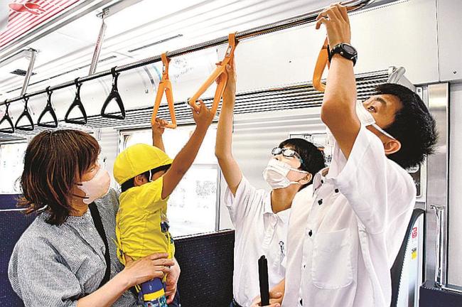 電車内の優先席付近のつり革が他より大きいことを触って確かめる生徒ら＝松江市中原町、松江しんじ湖温泉駅