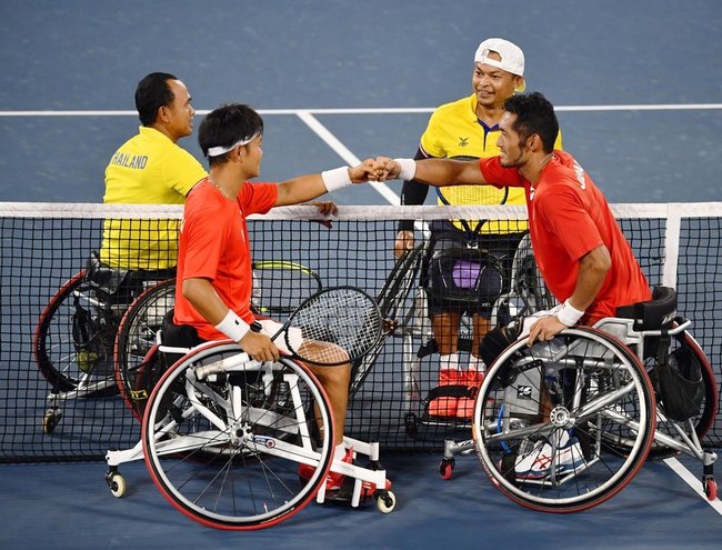 男子ダブルス１回戦に勝利し、拳を合わせる荒井（手前右）、三木組＝有明テニスの森公園
