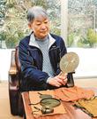 遊那御前が持っていたとされる鏡を手にする門脇順子さん＝島根県飯南町井戸谷、谷公民館