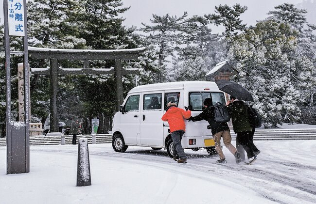 坂道でスリップし、動けなくなった自動車を押す観光客＝７日午前１０時２０分ごろ、出雲市大社町杵築南（画像の一部を加工しています）
