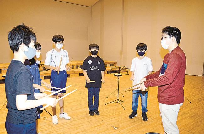 パーカッションの体験会で、杉原響平さん（右）から、ばちの使い方を学ぶ吹奏楽部員たち＝雲南市加茂町宇治、ラメール