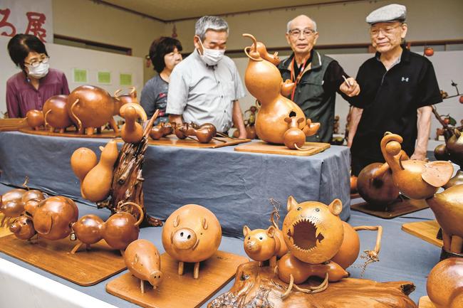 来館者にヒョウタン作品を説明する三成猪一さん（右から２人目）＝出雲市多伎町口田儀、多伎文化伝習館