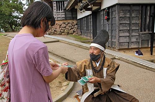 観光客にオリジナルステッカーを渡してもてなす本間隊長