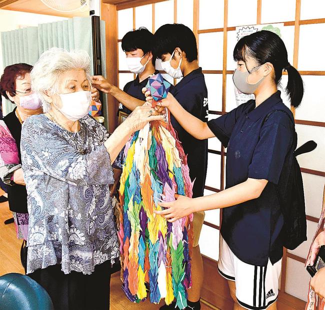 江津高ハンドボール部員に千羽鶴を手渡す施設利用者＝江津市和木町、よろこぼう屋