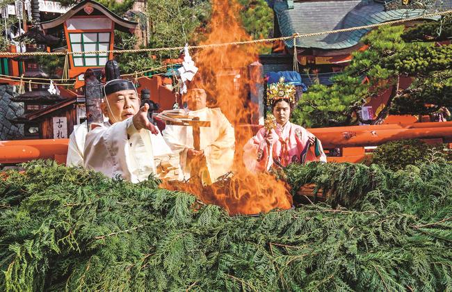 燃えさかる炎に火焚串を投げ入れる角河和幸宮司＝島根県津和野町後田、太皷谷稲成神社