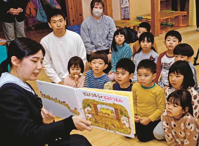 吉川莉央部長（左）が読む絵本に見入る園児＝出雲市神西沖町、出雲サンサン保育園