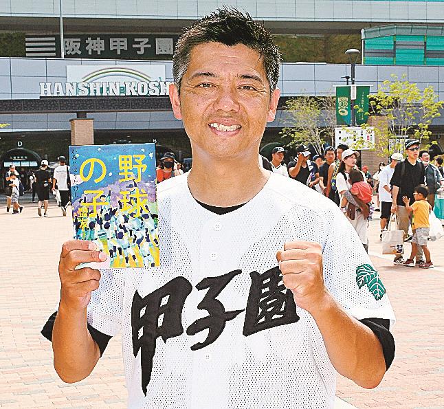 著書「野球の子　盟友」を手にするかみじょうたけしさん＝兵庫県西宮市、阪神甲子園駅駅前広場