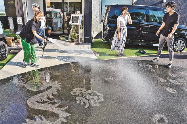水にぬれアスファルトに浮かび上がるアート作品＝松江市西尾町、ＮＲ－Ｃ