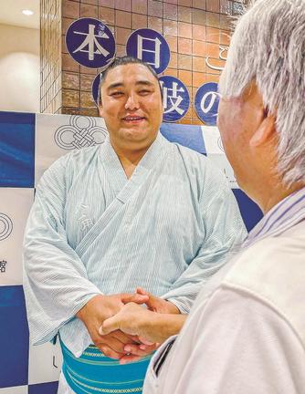 来場者と笑顔で握手を交わす君ケ浜親方＝東京都千代田区、日比谷しまね館