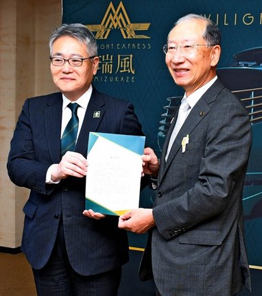 大田市の楫野弘和市長（右）に瑞風の立ち寄り観光地の決定通知書を手渡すＪＲ西日本山陰支社の佐伯祥一支社長＝同市大田町、市役所