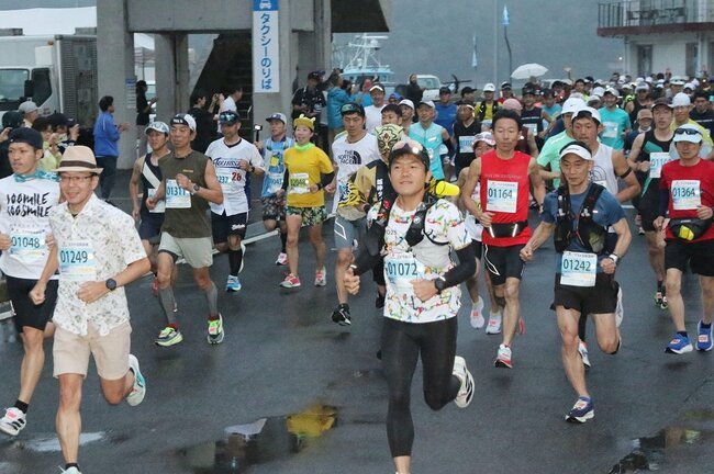 小雨が降る中、スタートする１００キロの部のランナーたち＝島根県隠岐の島町中町