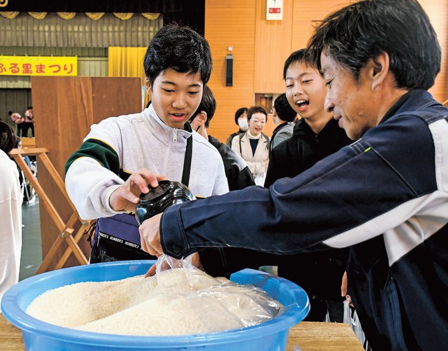 新米のすくい取りに挑戦する来場者＝浜田市旭町今市、市民体育館