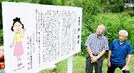 林春生さんの功績を伝える看板を眺める地域住民＝大田市大屋町