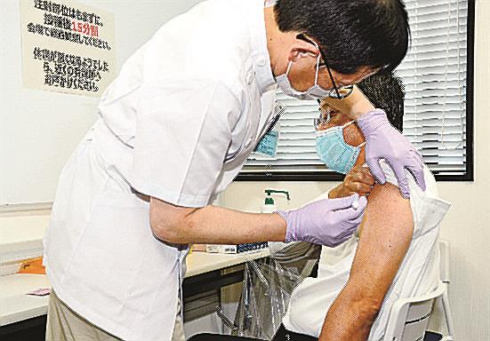 感染制御部の千酌浩樹教授（左）からワクチン接種を受ける原田省病院長＝米子市西町、鳥取大医学部付属病院