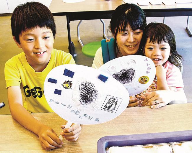 作ったうちわを手に笑顔を見せる参加者＝出雲市大社町杵築東、島根県立古代出雲歴史博物館