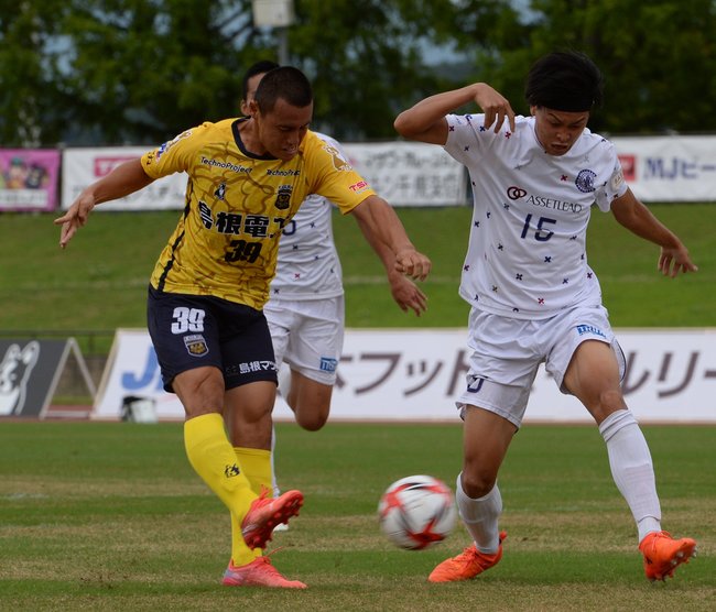 前半７分、ＦＣ神楽しまねのＦＷ谷尾昂也（左）がシュートを決め、１ー０とする＝松江市営陸上競技場