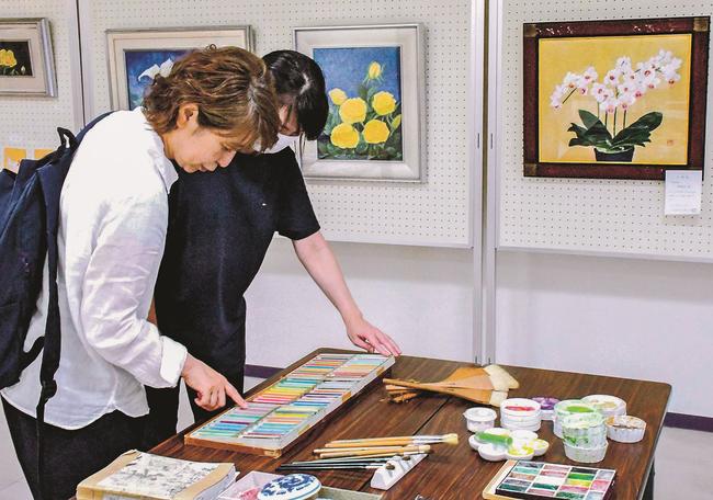 伊藤房子さんが使っていた画材を見る来場者＝松江市白潟本町、スティックビル