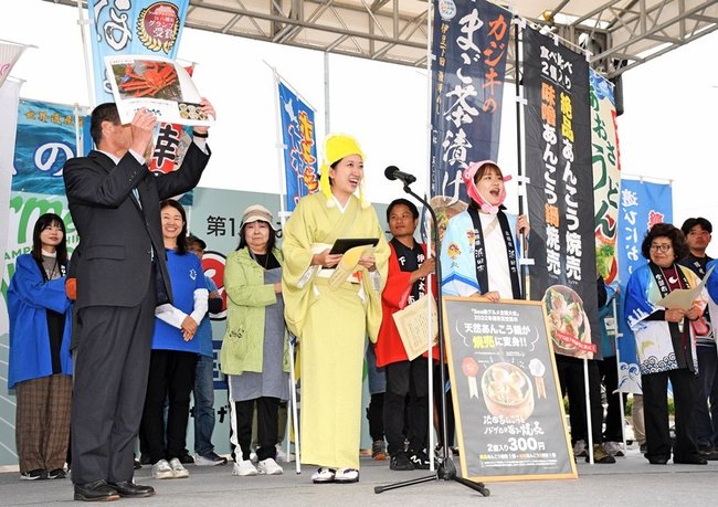 ステージ上で祝福されて笑顔を見せる、みなとオアシス浜田の増田可夏子さん（前列左から２人目）と竹林優花さん（同３人目）＝境港市竹内団地、境夢みなとターミナル駐車場の特設ステージ