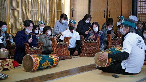 梅田英春教授（右）に教わりながら、ガムランの楽器演奏を体験する参加者＝島根県美郷町粕渕、浄土寺