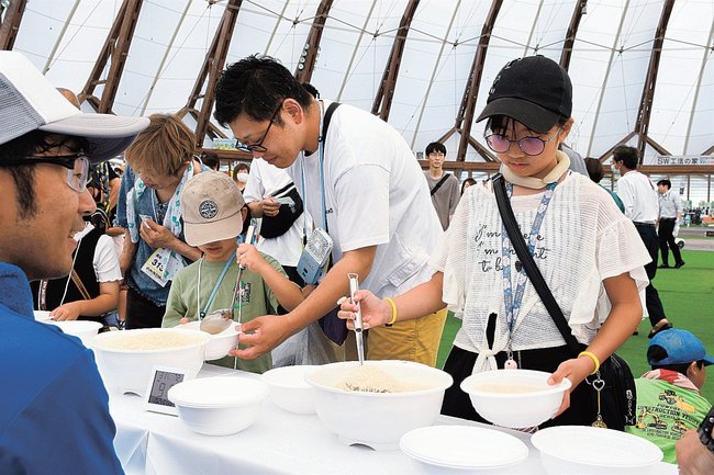 コメの重さ５００グラムを当てる企画で、コメをすくう参加者＝出雲市矢野町、出雲ドーム