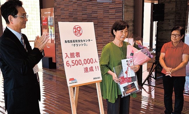 入館者６５０万人目となり、記念品を受け取る米田永子さん（左）＝益田市有明町、島根県芸術文化センター・グラントワ