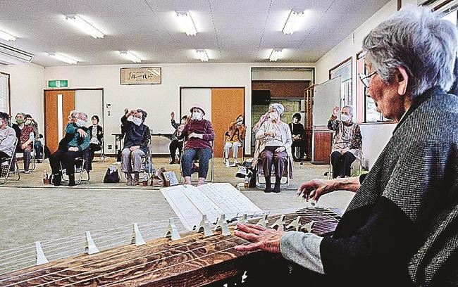 陶山和実さん（右）の演奏に合わせて体を動かす参加者＝松江市黒田町、黒田町集会所