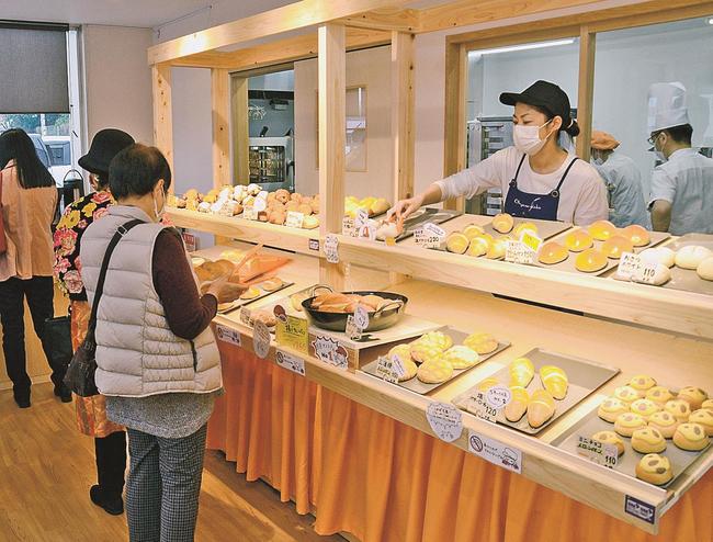 オープンしたばかりの店内でパンを買い求める来店客＝安来市安来町