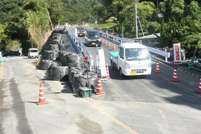 緊急車両用道路を通って地区外に出る住民の車両。左側が崩落現場（写真の一部を加工しています）＝出雲市大社町日御碕