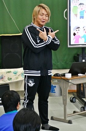 児童の質問に答え、決めのポーズをする日高郁人さん＝益田市高津１丁目、高津小学校