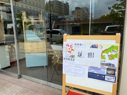 「どんちっちアジ」販売会場となる施設のポスターに「延期」と書いてもらった＝大分県日田市元町