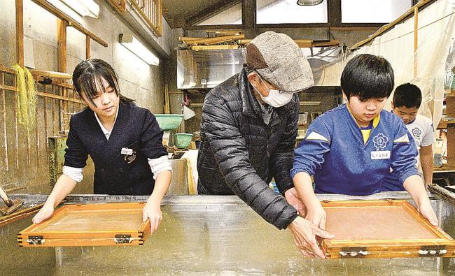 佐々木誠さん（中央）の手ほどきで卒業証書用の紙すきに挑戦する児童＝江津市桜江町長谷、風の工房