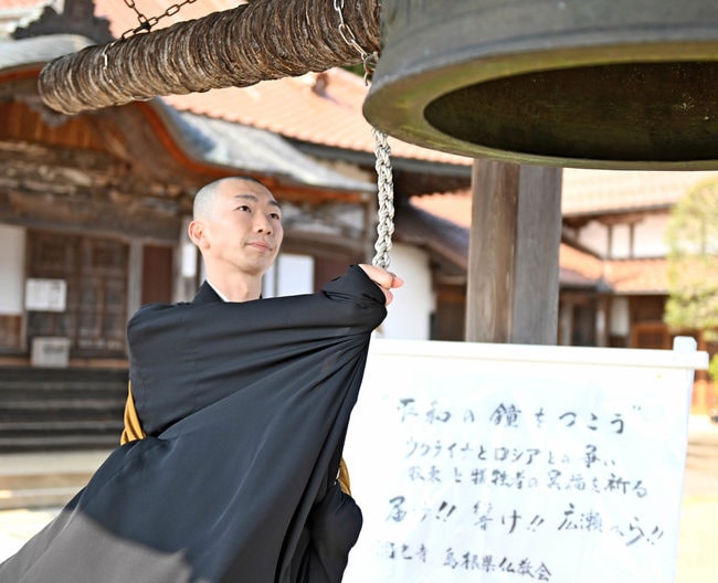 ウクライナ国民に穏やかな朝が来ることを願い、鐘をたたく僧侶＝安来市広瀬町広瀬、洞光寺