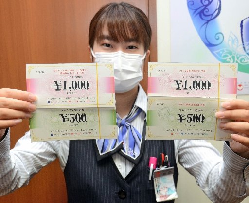 プレミアムお買い物券の見本を手にする一畑百貨店の店員＝松江市朝日町
