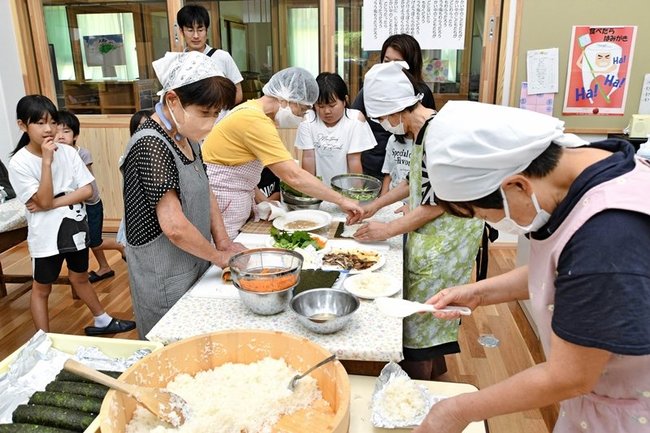 地元住民の調理作業を見学する真砂小の児童たち＝益田市波田町、市立地域活性化交流館