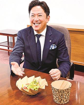おりがみカップの特徴を説明する湯川惣一郎社長＝松江市殿町、島根県庁