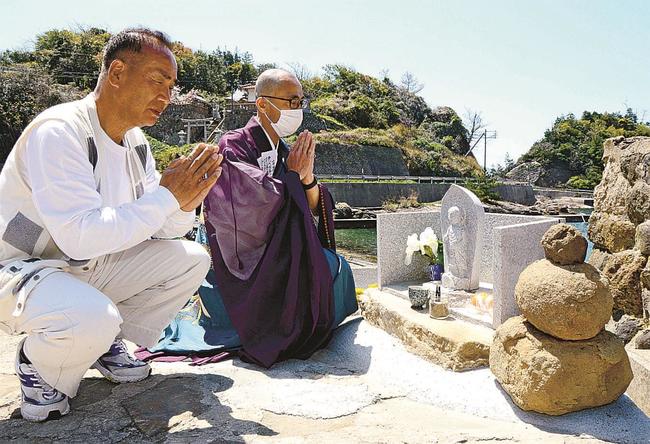 風化した五輪塔（手前右）に替えて建てた尼子地蔵に手を合わせる若松隆さん（左）と池田哲真住職＝松江市鹿島町手結